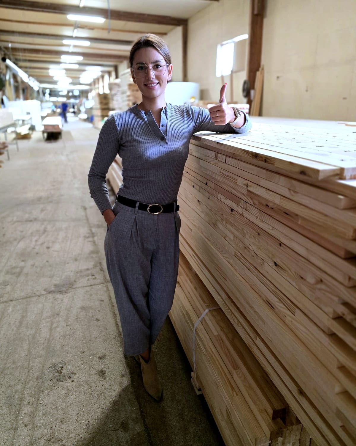 Drewno Pilarscy team member beside a pack of sawn timber in the mill hall